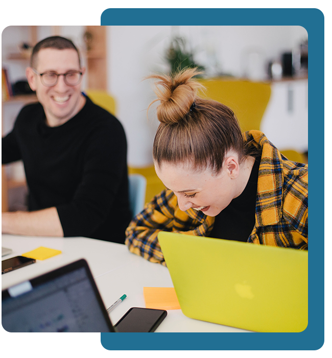 woman at laptop laughing with a colleague
